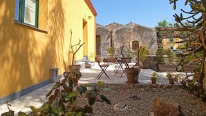 Un edificio amarillo con un patio amoblado y macetas con plantas.