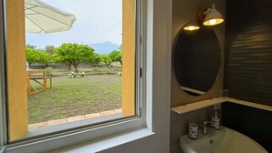 Un baño con ventana, lavamanos y espejo.