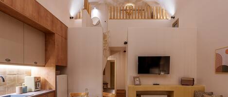 A modern kitchen with wooden cabinets, a dining area with a round table and chairs, a built-in TV, and a fireplace.