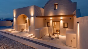 A modern building with a dome-shaped roof, outdoor seating area, and a well-lit entrance. - Living Moments (Santorini)