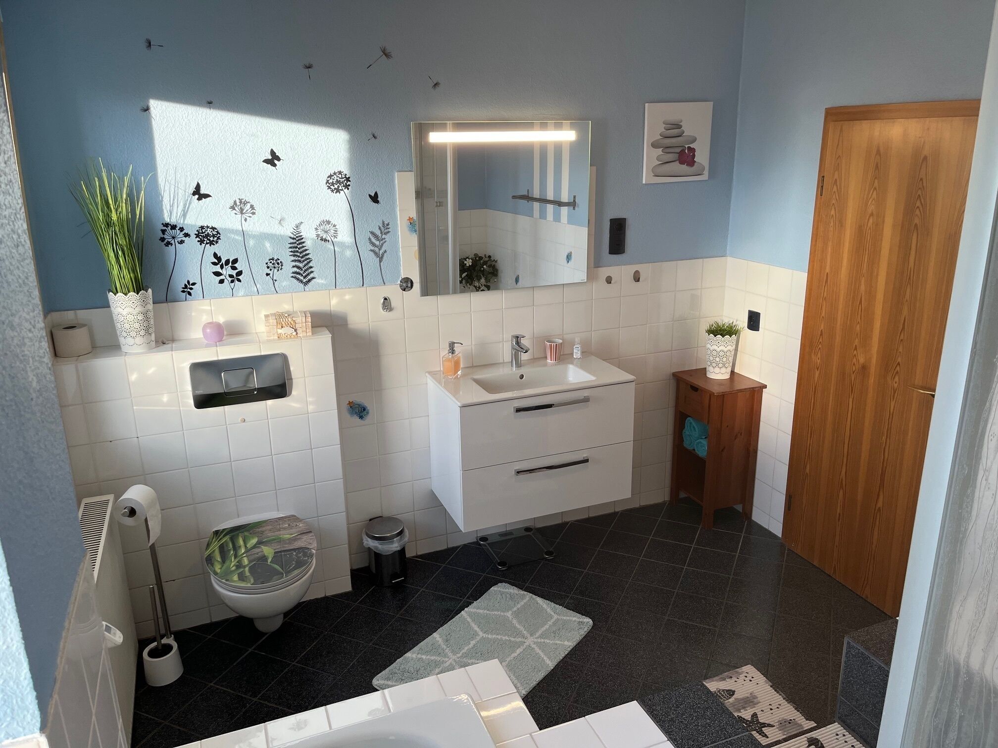 A modern bathroom with a toilet, sink, and mirror.