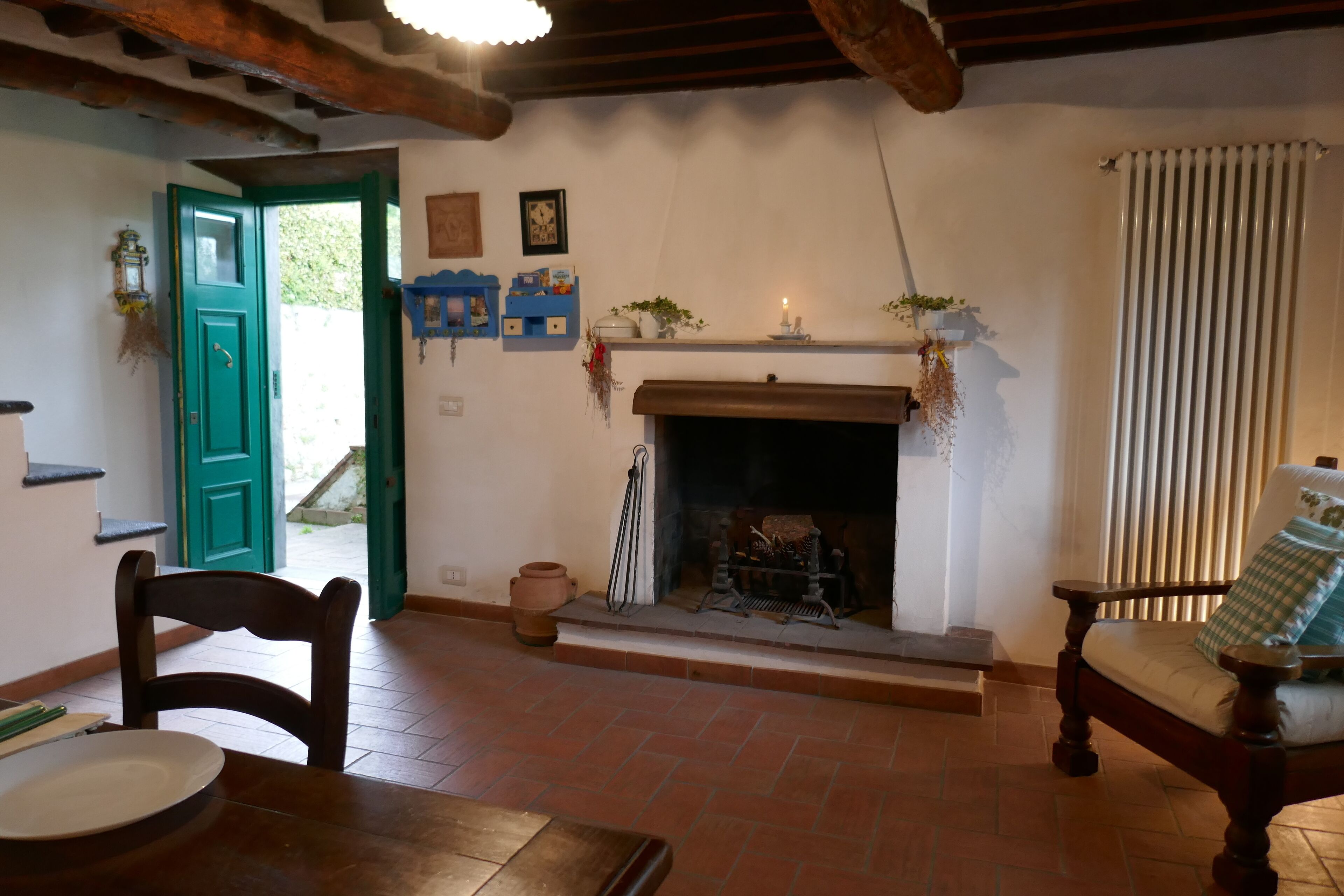 Una habitación rústica con chimenea, una mesa de comedor con sillas y una puerta verde que da al exterior.