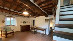 A rustic kitchen with a wooden table, a bench, and a window with shutters. - Charming house in old stone wall village (Fibbiano)
