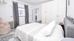Ein Schlafzimmer mit einem großen Bett, einem Sessel, einem Kleiderschrank und einer Heizung.