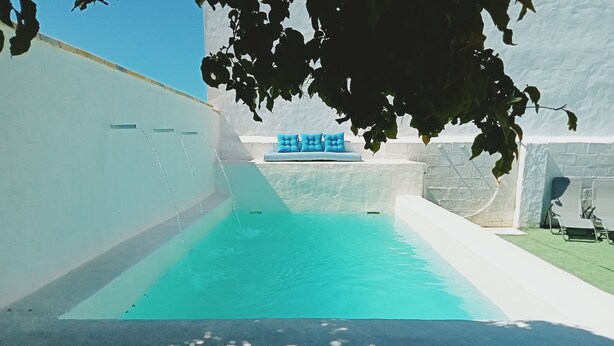 Ein Pool mit blauer Färbung, umgeben von weißen Wänden und einer Steinstruktur.