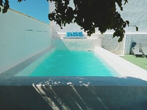 A swimming pool with a blue hue, surrounded by white walls and a stone structure. - House in Costa Cadis Villa Buganvillas (Chiclana de la Frontera)