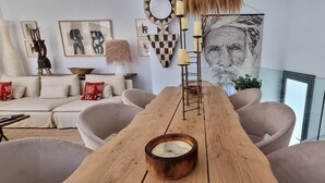 A modern living room with a wooden dining table, beige sofas, and a large abstract painting.