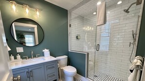 Ein modernes Badezimmer mit Duschkabine aus Glas, einem weißen Waschbecken und einer Toilette.