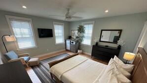 Ein Schlafzimmer mit Bett, Schminktisch, Schreibtisch, Stuhl und Deckenventilator.