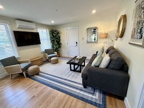 Relax in this stylish living room with a grey sofa, wicker chair, and flat-screen TV.