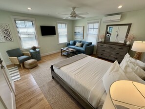 Een slaapkamer met een bed, een bank, een bijzettafeltje, een dressoir en een plafondventilator.