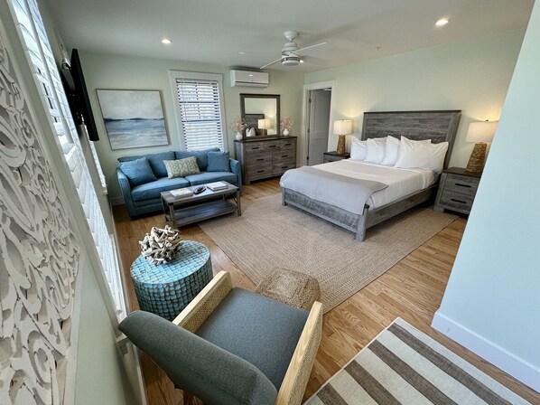 Een slaapkamer met een bed, een bank, een bijzettafeltje, een stoel, een dressoir en een nachtkastje.