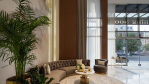 Un salon moderne avec un canapé d’angle aux lignes courbes, une table basse ronde et une grande plante en pot.