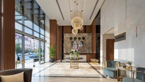 Een moderne lobby met een marmeren vloer, een receptiebalie en zithoeken.