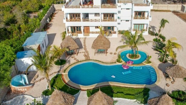 A resort with a large swimming pool, multiple guest rooms, and thatched umbrellas. - HABER HOTEL & SPA (Matemwe)