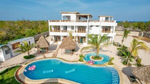 A resort with a large swimming pool, multiple balconies, and a beachside location. - HABER HOTEL & SPA (Matemwe)