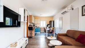 Una sala de estar moderna con un televisor grande, un sofá marrón y un comedor con mesa y sillas.