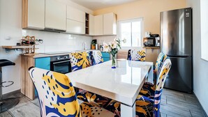Una cocina moderna con comedor, que incluye un refrigerador de acero inoxidable, un microondas y una mesa de comedor con sillas de colores.