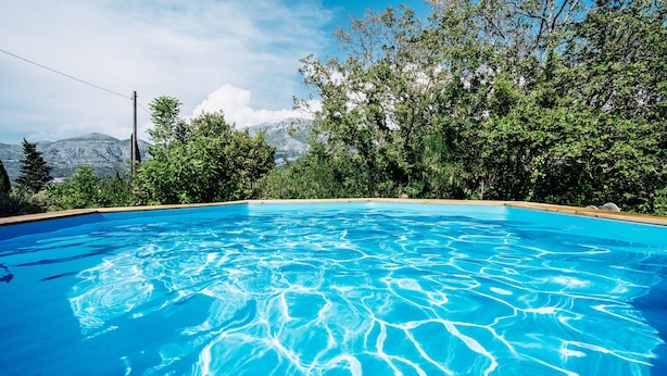Una piscina azul cristalina rodeada de exuberante vegetación y montañas al fondo.