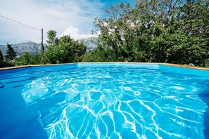 Una piscina azul cristalina rodeada de exuberante vegetación y montañas al fondo.
