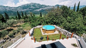 Una piscina rodeada por una terraza de madera, con vistas a montañas y árboles al fondo.