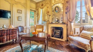 A classic room with a fireplace, ornate furniture, and a television.