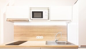 Una cocina con microondas, un lavabo y armarios de madera.