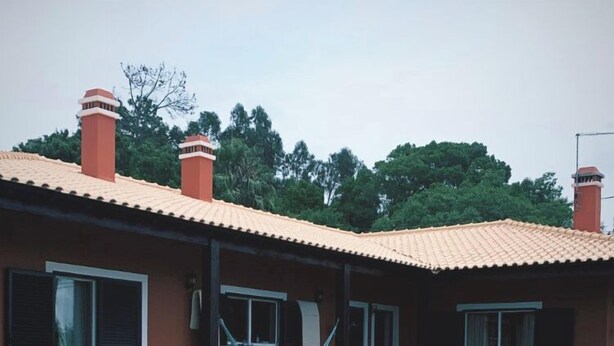 Vue sur une maison avec un toit en tuiles, un hamac et une piscine d’un bleu éclatant, le tout vu depuis le bord de la piscine.