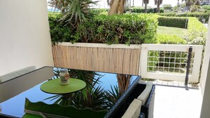 A patio with a glass table, a green umbrella, and a bottle of water. - Studio Canet Plage (CANET PLAGE)