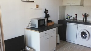 A compact kitchenette with a microwave, a small sink, and a washing machine. - Studio Canet Plage (CANET PLAGE)