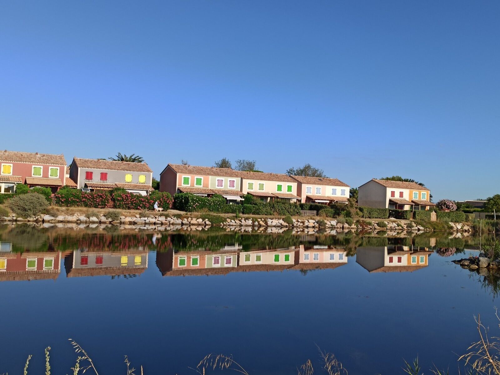 A row of colorful houses by a calm lake with clear reflections.