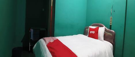 A room with a bed, green walls, and a red and white bedspread.