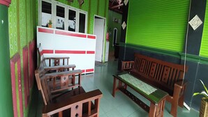 Una habitación con decoración en tonos verde y blanco, que incluye un banco de madera, una mesita y un armario blanco con ventana.