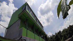 Un edificio verde con numerosas ventanas y un balcón.