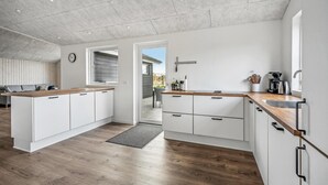 Une cuisine moderne avec des armoires blanches, des comptoirs en bois et une grande fenêtre.