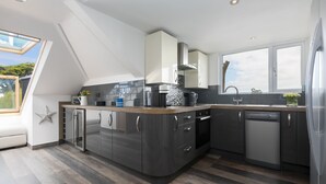 A modern kitchen with a skylight, dark cabinetry, and a dishwasher. - Willows - Sleeps 6 - On-site Parking - Outside Space (St Ives)
