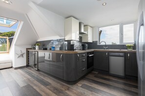 A modern kitchen with a skylight, dark cabinetry, and a dishwasher. - Willows - Sleeps 6 - On-site Parking - Outside Space (St Ives)