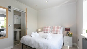 A bedroom with a bed, bedside table, lamp, and a mirror.