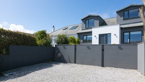A modern house with a gravel driveway, grey walls, and a well-maintained garden. - Willows - Sleeps 6 - On-site Parking - Outside Space (St Ives)