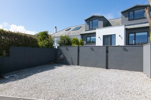 A modern house with a gravel driveway, grey walls, and a well-maintained garden. - Willows - Sleeps 6 - On-site Parking - Outside Space (St Ives)