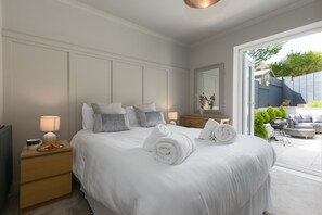 A neatly made bed with rolled towels, a bedside table with a lamp, and a view of the outdoor patio area. - Willows - Sleeps 6 - On-site Parking - Outside Space (St Ives)