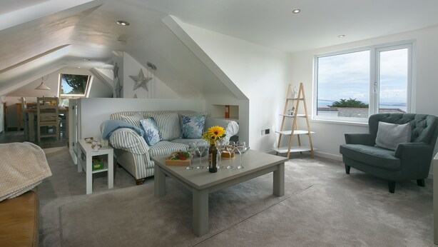 A modern living room with a loft bedroom, a dining area, and a large window with a view. - Willows - Sleeps 6 - On-site Parking - Outside Space (St Ives)