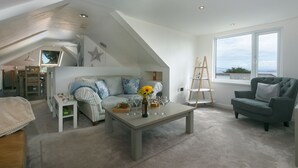 A modern living room with a loft bedroom, a dining area, and a large window with a view.