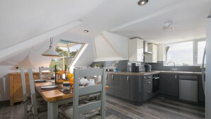 A modern kitchen with a dining area, wooden flooring, and a skylight.
