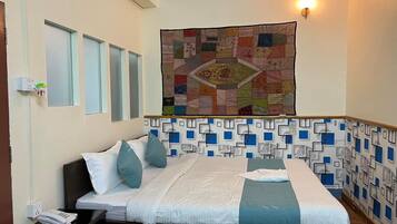 A hotel room with a bed, a bedside telephone, a wall tapestry, and a patterned wall design.
