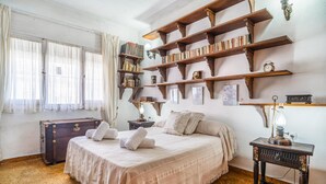 Een slaapkamer met een groot bed, een houten boekenkast, een dressoir en een nachtkastje.