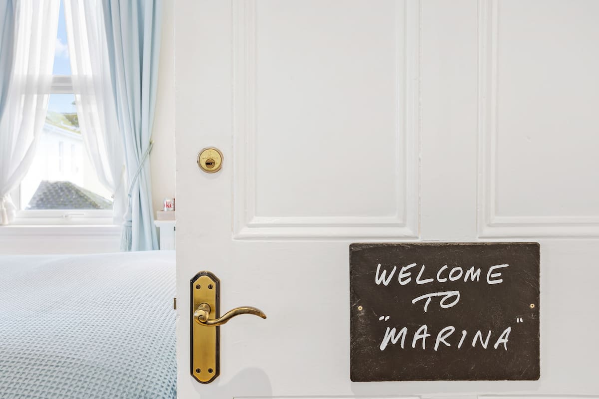 A white door with a brass handle and a sign that reads "WELCOME TO MARINA".
