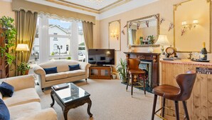A living room with a sofa, a television, a bar area, and a fireplace. - Kingston House (Torquay)