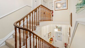 A multi-level interior with a wooden staircase, white walls, and a framed picture on the upper level. - Kingston House (Torquay)