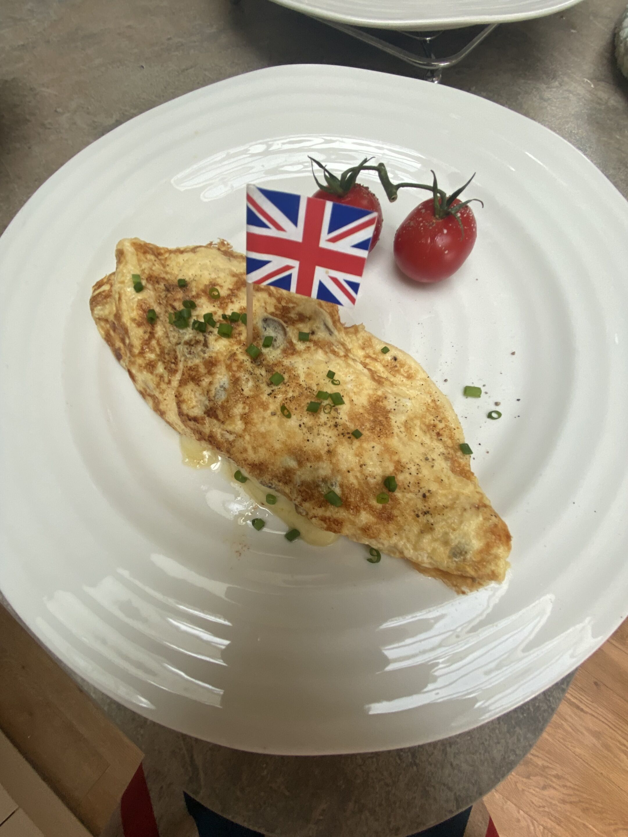 A plate with an omelette, a small flag, and a tomato.